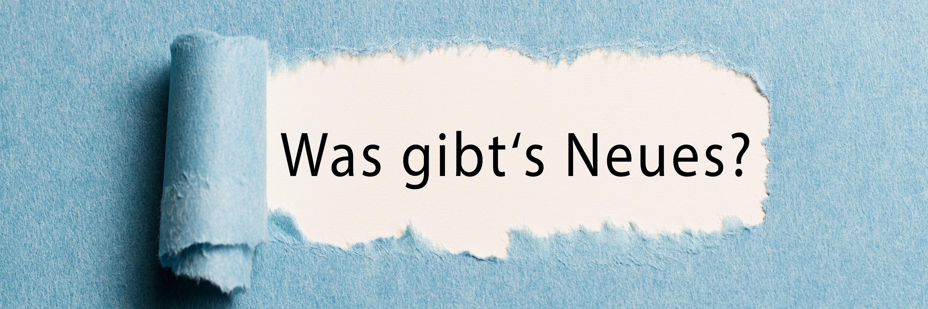 torn paper revealing the phrase "what's new?" in German